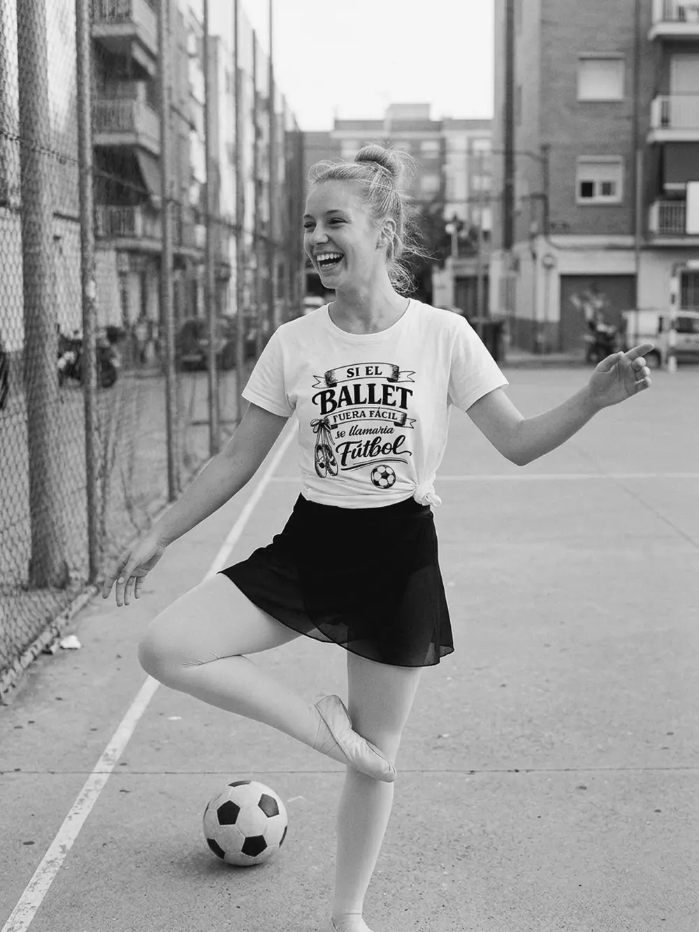 Bailarina con falda de ballet tocando un balón en una pista de barrio, con la camiseta blanca Si el ballet fuera fácil se llamaría fútbol