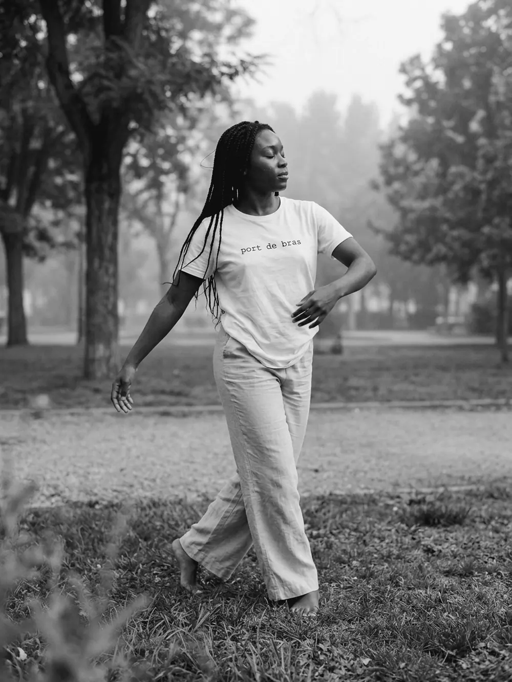 Bailarina descalza bailando en un parque con la camiseta blanca port de bras